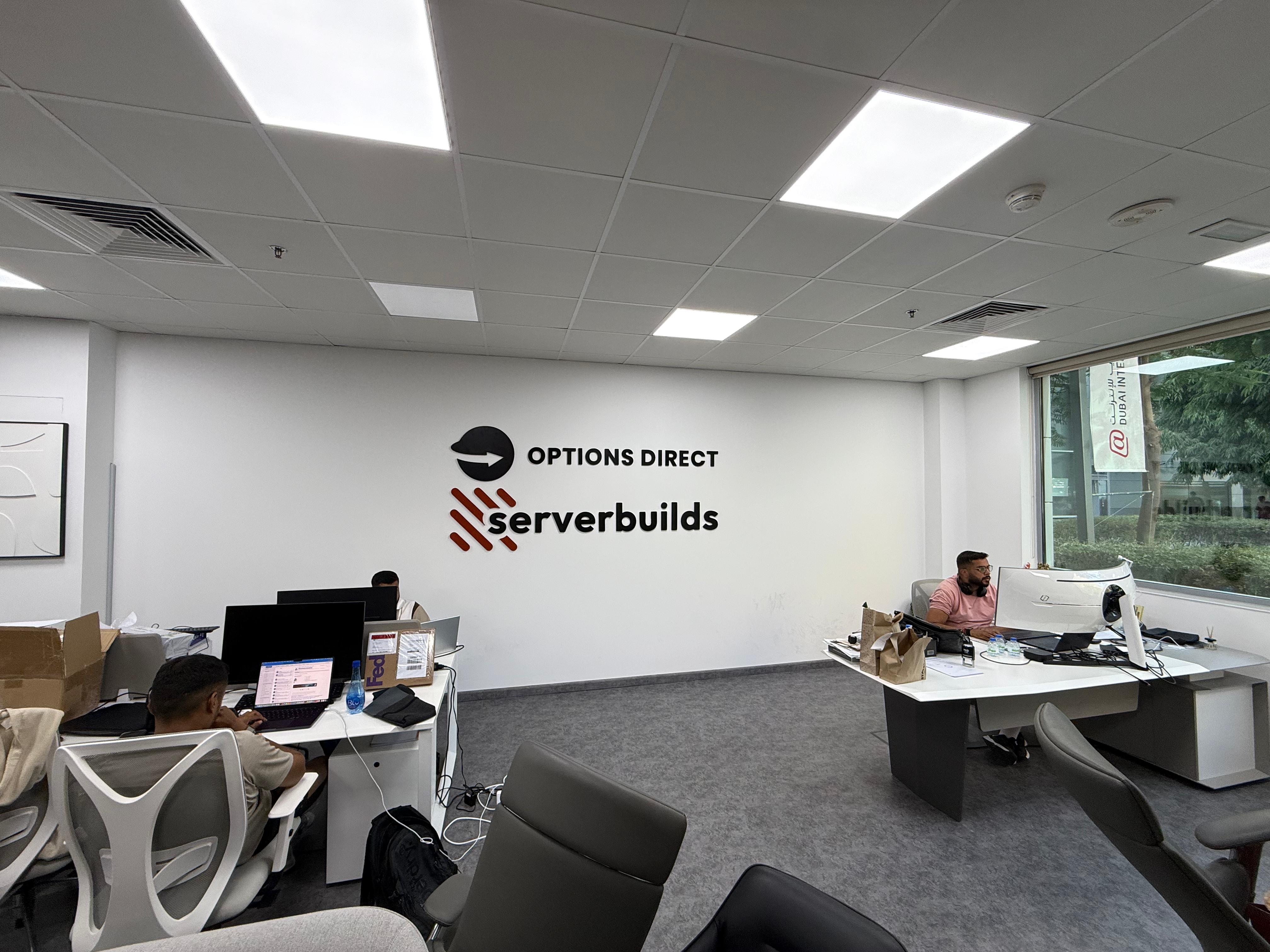 Options Direct and ServerBuilds team at work in the Dubai Internet City office, with the company signage on the wall behind them